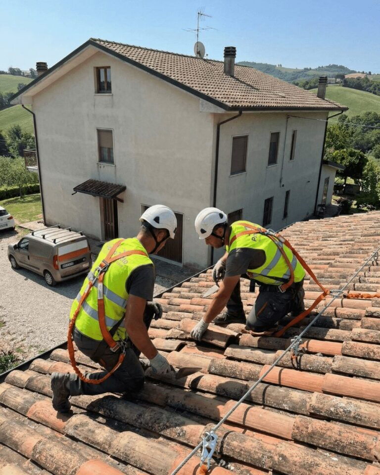 Due operai Pronto Tetto agganciati alla linea vita lavorano su un tetto in coppi